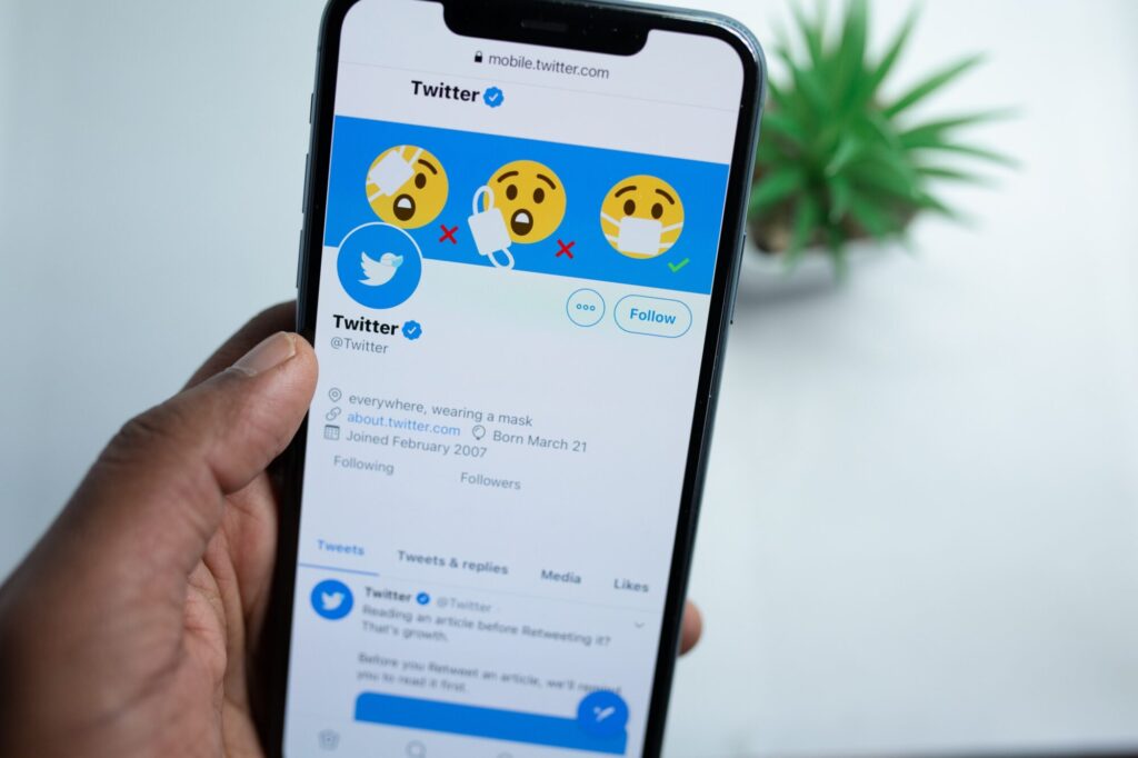 An image of a hand holding a smartphone using Twitter