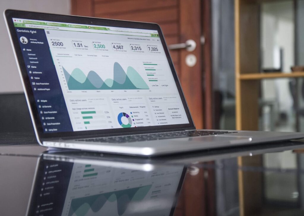 Laptop displaying digital marketing analytics, featuring data visualizations like line graphs and pie charts, possibly illustrating website performance, user engagement, and sales metrics, with a reflection on a glossy surface.