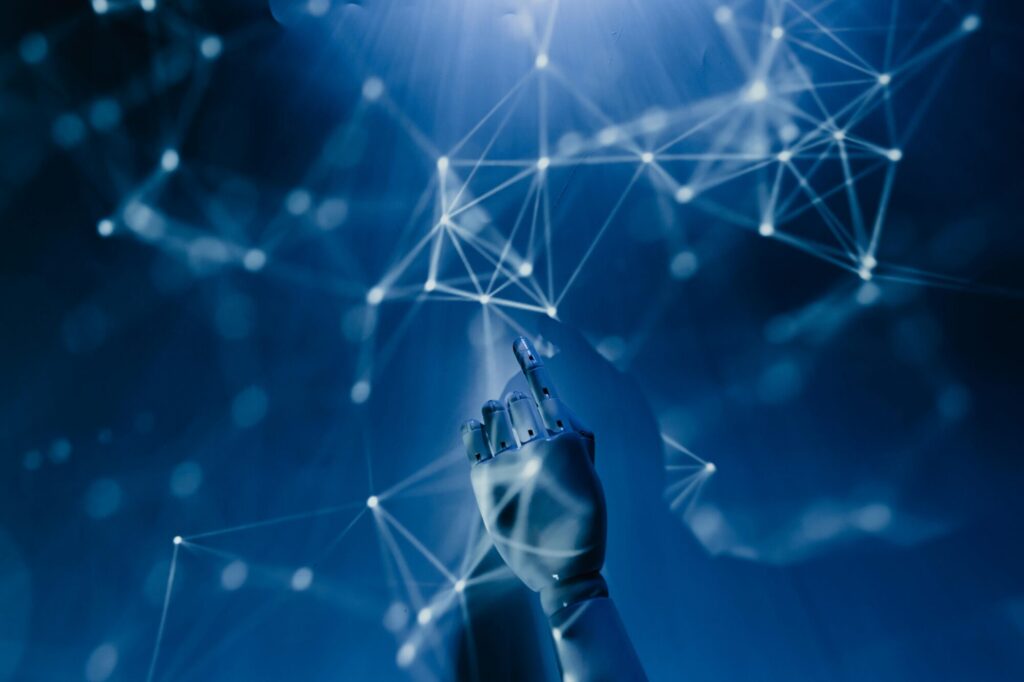 Robotic hand pointing upwards, overlaid on a network of interconnected nodes and lines, illuminated with blue light.