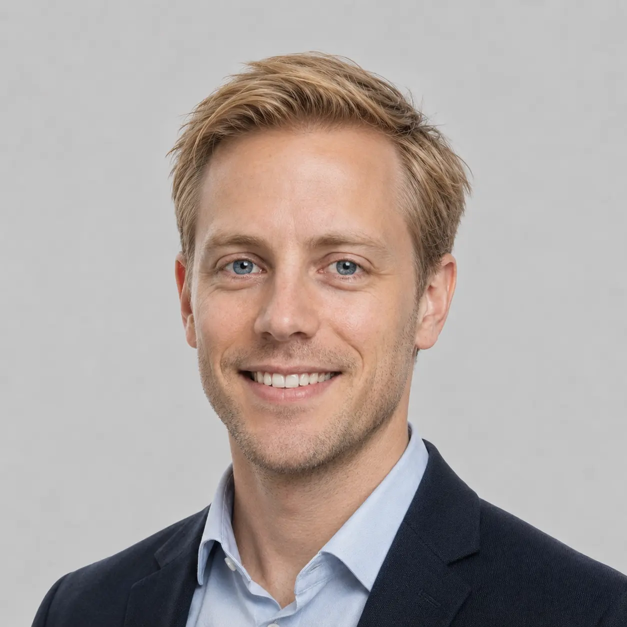 Daniel our lead developer - blonde, slightly scruffy hair and stubble, blue eyed man wearing shirt and suit jacket.